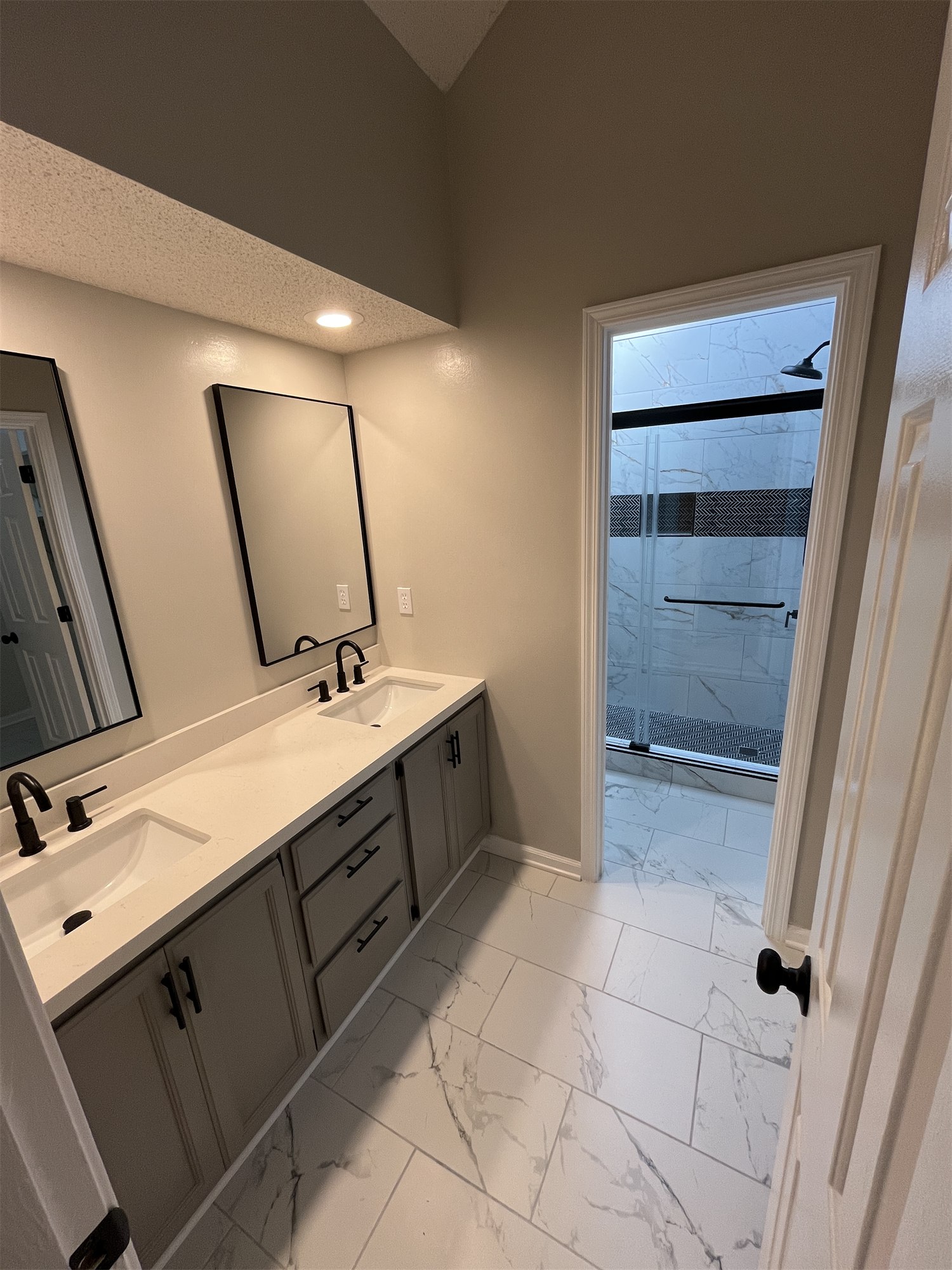Completed bathroom with a double vanity, mirror, and glass shower