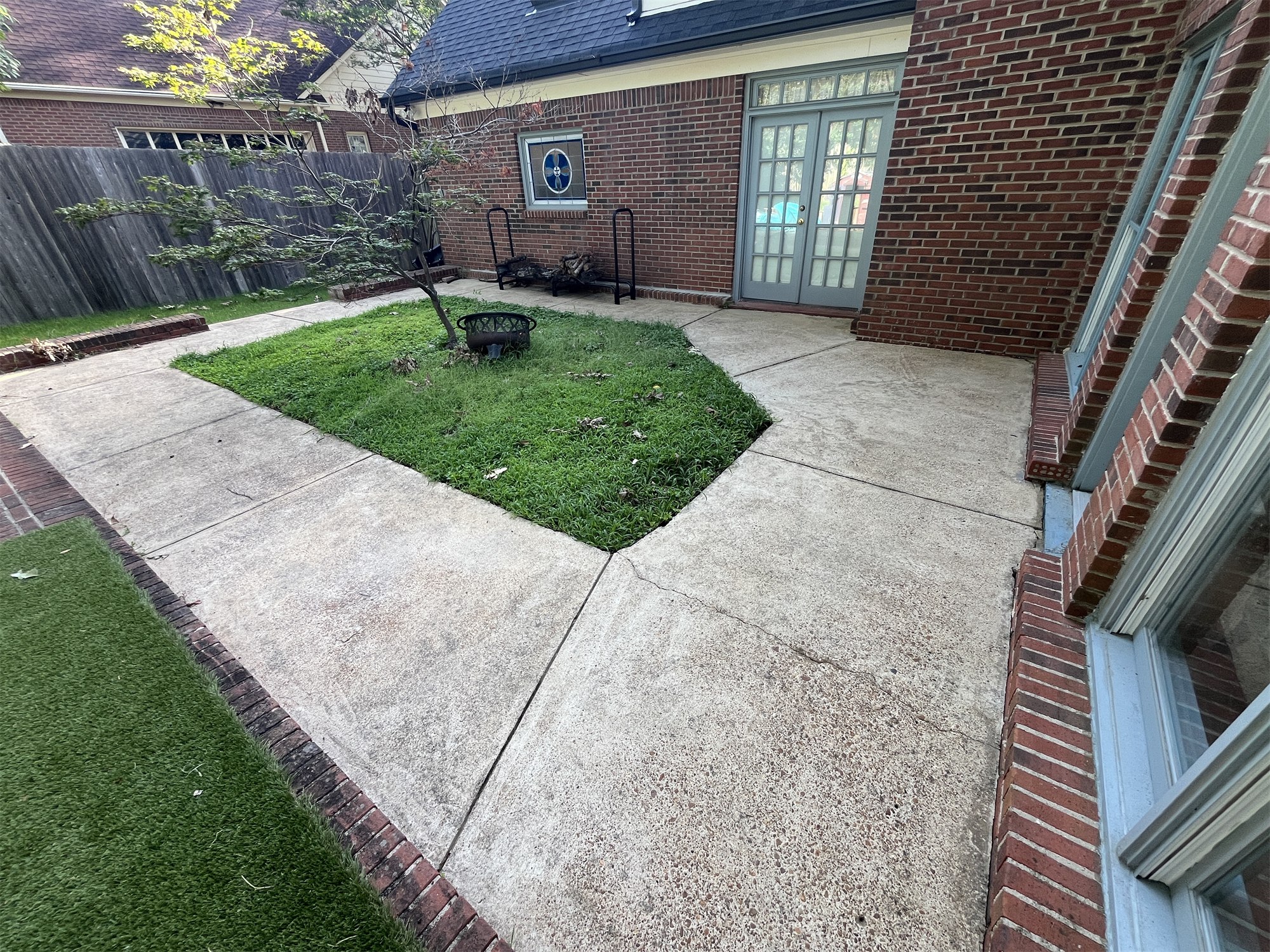 Cleaned concrete patio and walkway beside a brick house